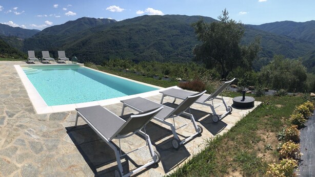 Una piscina con sillas de descanso y vistas a las montañas.