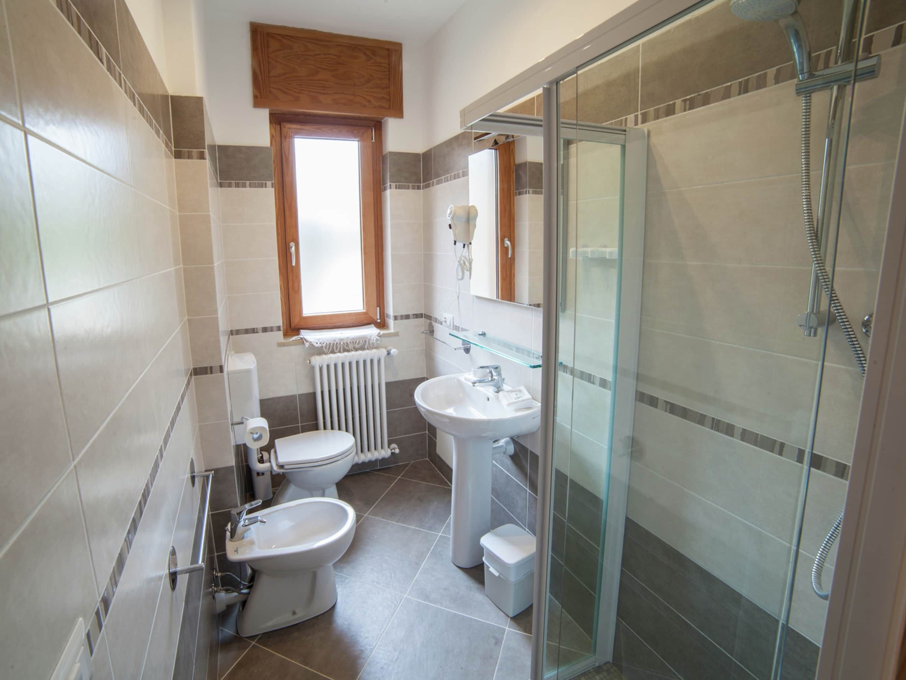 A modern bathroom with a glass-enclosed shower, a toilet, and a sink.