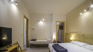 Una habitación de hotel con una cama, televisión y escritorio.