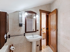 A bathroom with a white sink, a mirror, a towel rack, and a wooden door. - Belvilla by OYO Vigna Della Signora (Morano Calabro)
