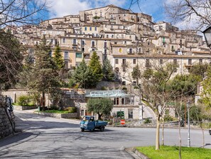 A street leading up to a hillside of buildings with a blue car parked on the side. - Belvilla by OYO Vigna Della Signora (Morano Calabro)