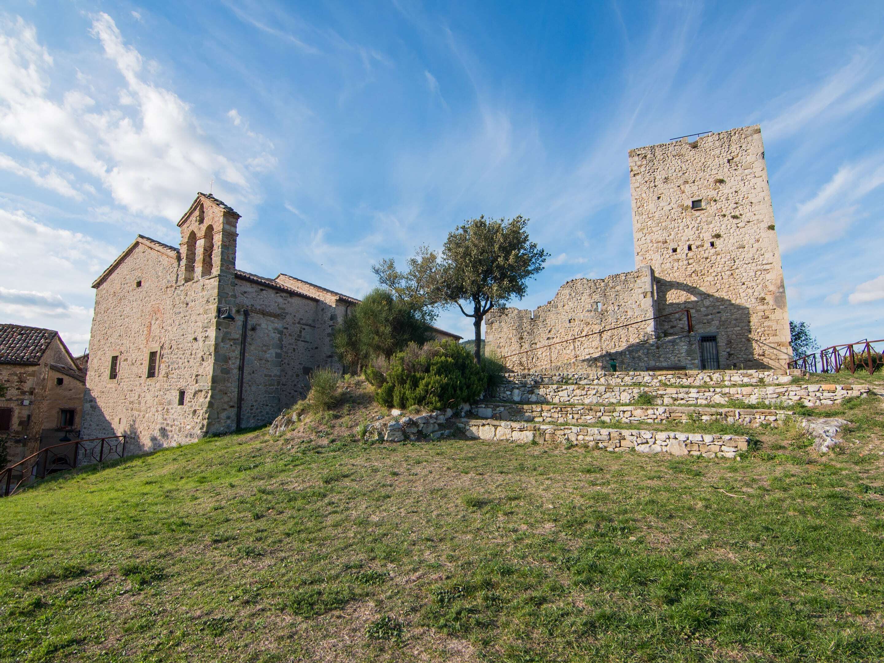 A historic stone building with a tower and a smaller building with a bell tower.
