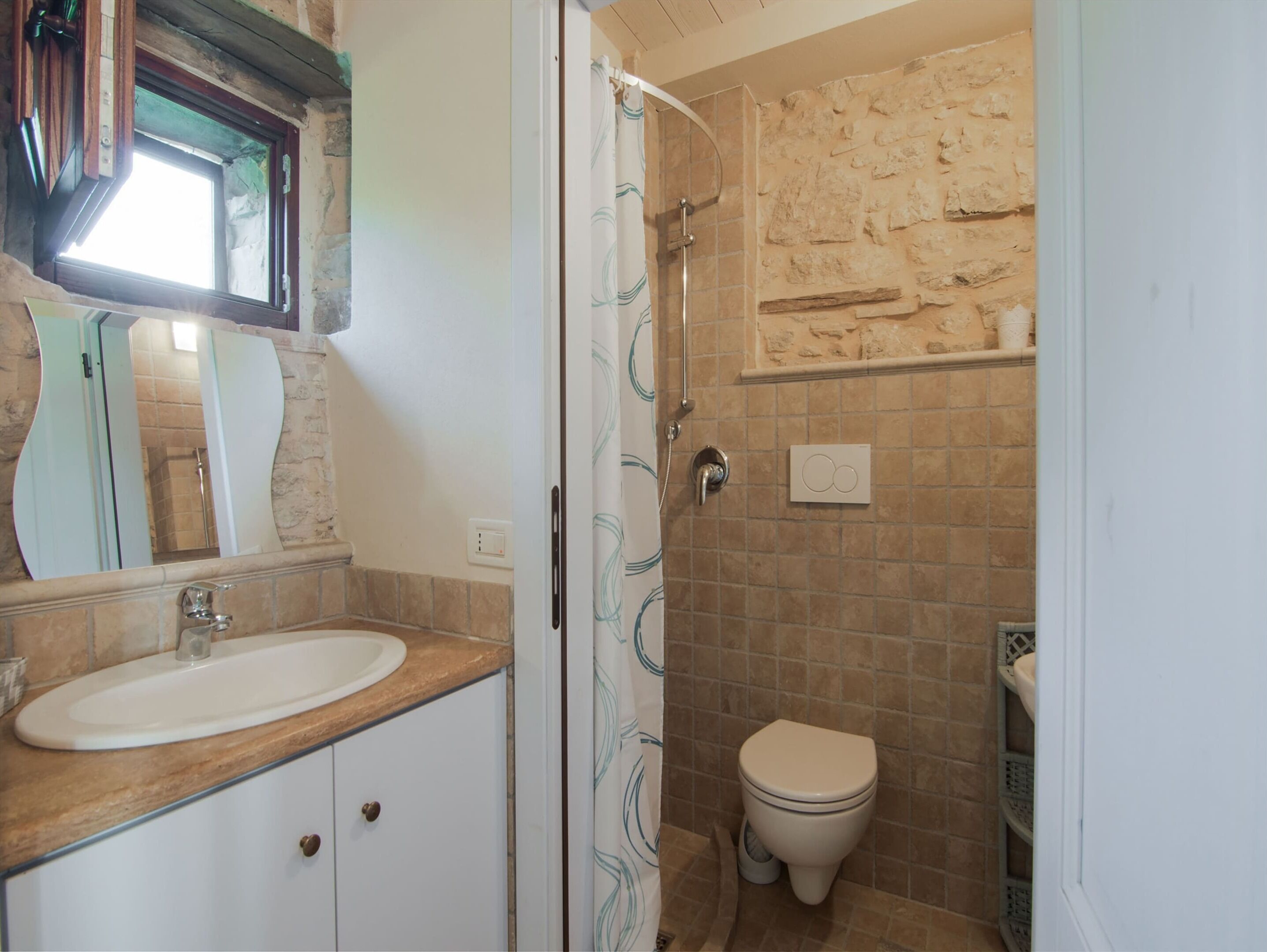 A bathroom with a sink, mirror, shower, and toilet.