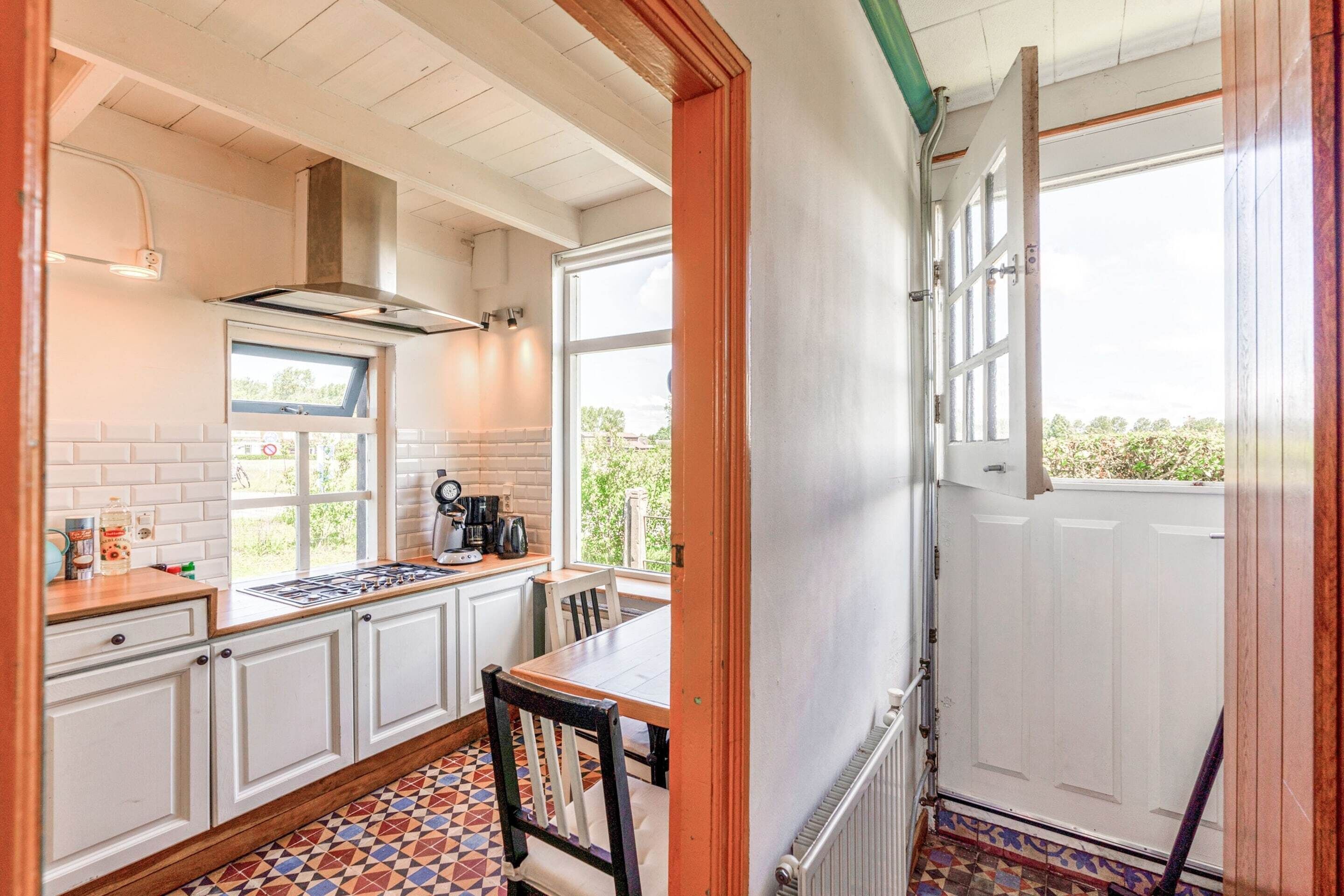 A kitchen with white cabinets, a tiled floor, a stove, and a window.