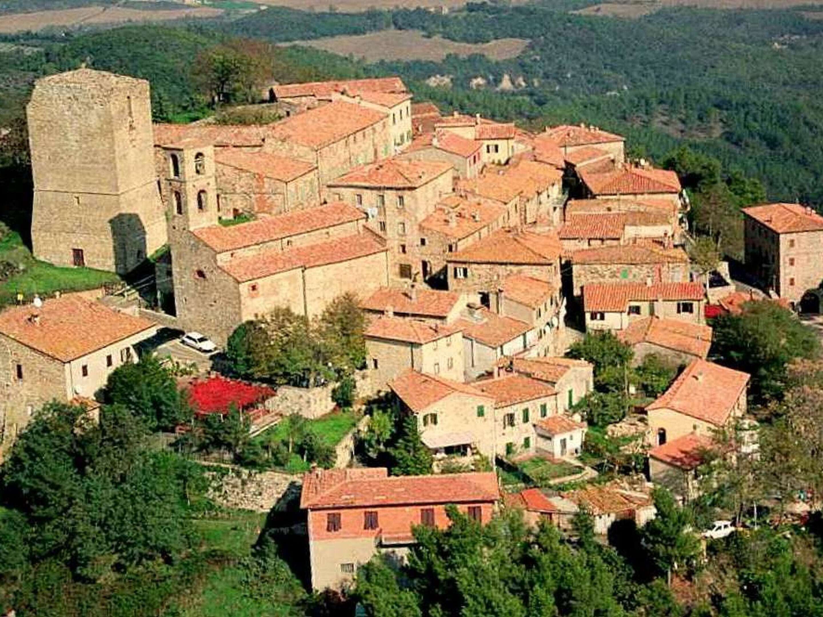 A historic town with a prominent tower and closely packed buildings with red-tiled roofs.