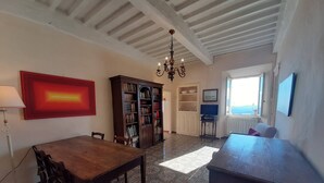 A dining area with a wooden table and chairs, a bookshelf, a chandelier, and a window with a view. - Cozy 2-bedroom Apartment (Castelnuovo di Val di Cecina)
