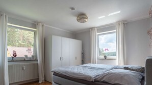 A bedroom with a bed, a wardrobe, a radiator, and a window with curtains. - Tranquil Apartment in Marktleuthen near River & Forest (Marktleuthen)