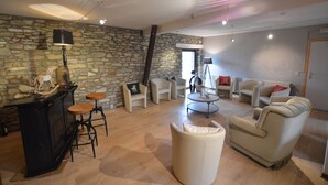 A living room with a stone wall, a black bar, and a round coffee table. - Group Escape in Vielsalm (Vielsalm)