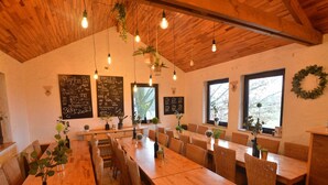 A restaurant with wooden tables and chairs, hanging light bulbs, and potted plants. - Group Escape in Vielsalm (Vielsalm)