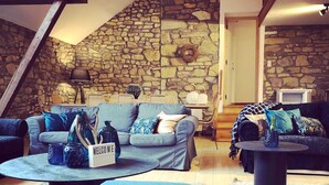 A cozy living room with a stone wall, a blue sofa set, a coffee table, and a fireplace. - Group Escape in Vielsalm (Vielsalm)