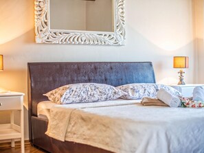 A neatly made bed with floral bedding, a dark headboard, and a decorative mirror above it. - Conventional Holiday Home in Umag With Private Pool (Umag)