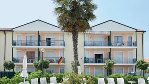 A multi-story hotel with balconies, outdoor seating, and a flag. - Belvilla by OYO Holiday Home in Rosolina (Rosolina)