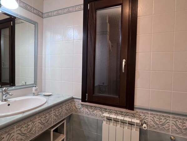 Une salle de bain avec un lavabo blanc, un miroir et une porte en bois foncé.