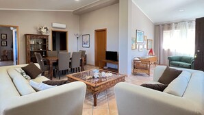 Un salón espacioso con comedor, televisión y un sofá verde.