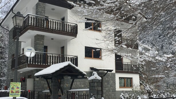 A multi-story building with balconies, a satellite dish, and a stone facade. - Serene Chalet in Antey-Saint-André near Ski Area (Antey-Saint-Andre)
