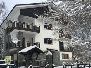 A multi-story building with balconies, a satellite dish, and a stone facade. - Serene Chalet in Antey-Saint-André near Ski Area (Antey-Saint-Andre)