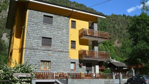 A two-story building with a stone facade, yellow upper walls, and balconies with wooden railings. - Serene Chalet in Antey-Saint-André near Ski Area (Antey-Saint-Andre)
