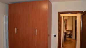 A room with a large wooden wardrobe, a radiator, and a doorway leading to a dining area with chairs and a table. - Serene Chalet in Antey-Saint-André near Ski Area (Antey-Saint-Andre)