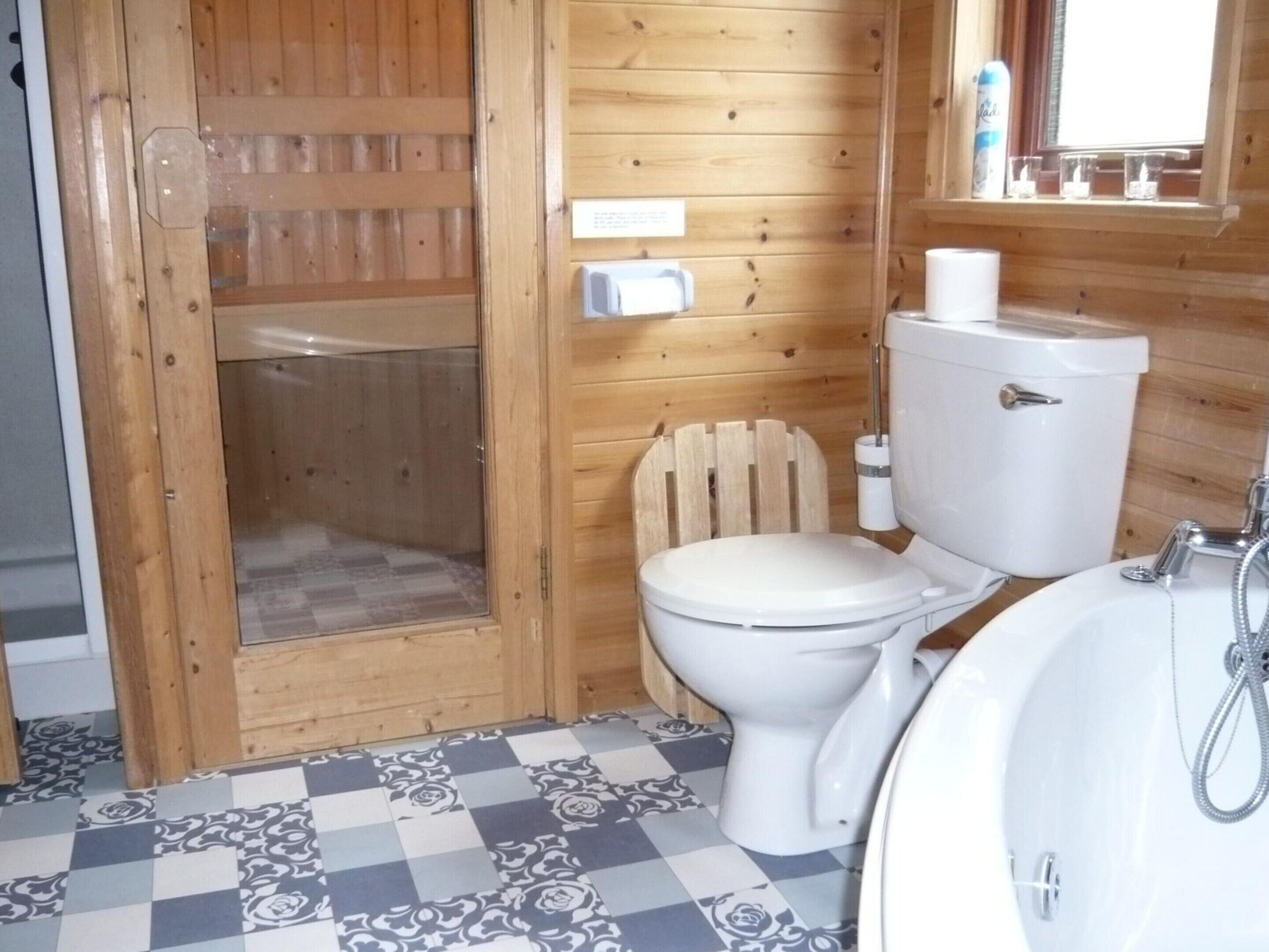 Et lille, kompakt badeværelse med toilet, vask og brusebad.