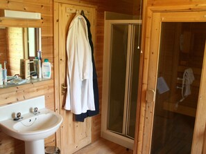 Une salle de bain en bois avec un lavabo, un miroir et une porte de douche en verre.