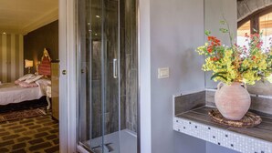 A modern bathroom with a glass shower enclosure, a large mirror, and a vase of flowers on the vanity. - Villa in Tuscany With Pool and Valley Views (Castiglion Fiorentino)