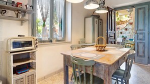 A rustic kitchen with a wooden table, vintage appliances, and a window with curtains. - Apartment in Stroncone Near Piediluco Lake (Stroncone)