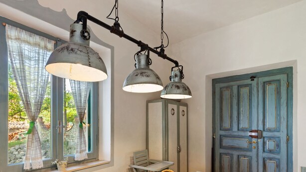 A dining area with a wooden table, two hanging lamps, a basket, and a blue door. - Apartment in Stroncone Near Piediluco Lake (Stroncone)