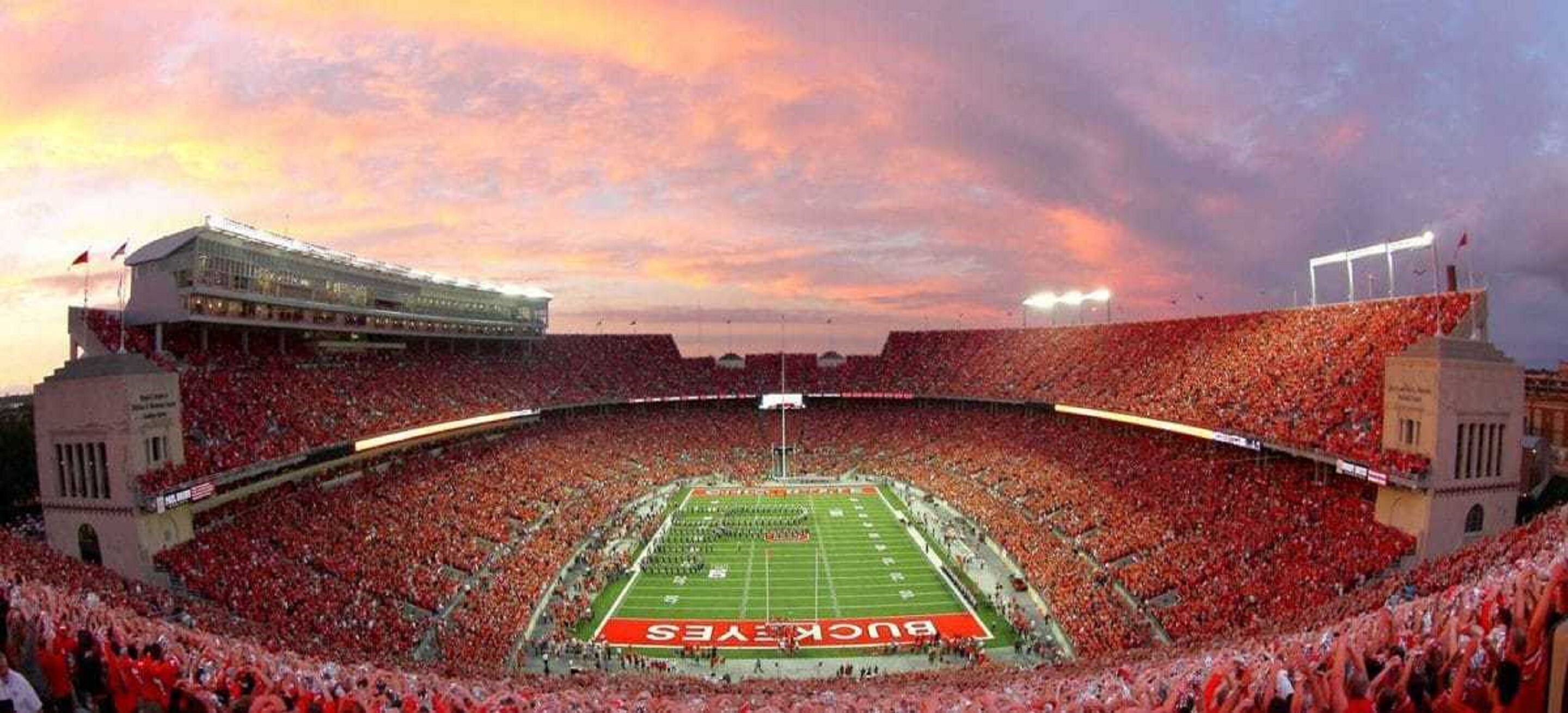 A stadium with a football field, surrounded by a large crowd of spectators.