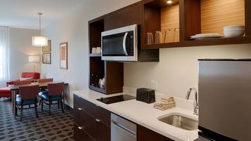 A modern kitchen with a built-in microwave, stainless steel appliances, and a dining area with a red chair and a table.