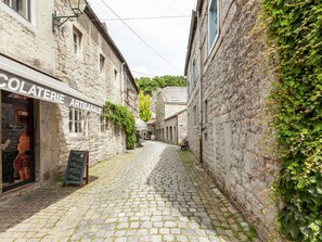 Eine enge Kopfsteinpflasterstraße, gesäumt von Gebäuden, wobei eines eine Schilder mit der Aufschrift 'COLATERIE ARTISANALE' trägt.