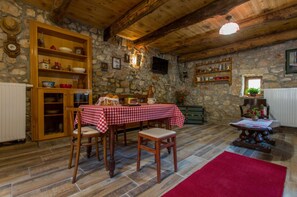 A rustic dining area with stone walls, wooden beams, and a checkered tablecloth. - Holiday Home in Polje Near Beach (Dobrinj)