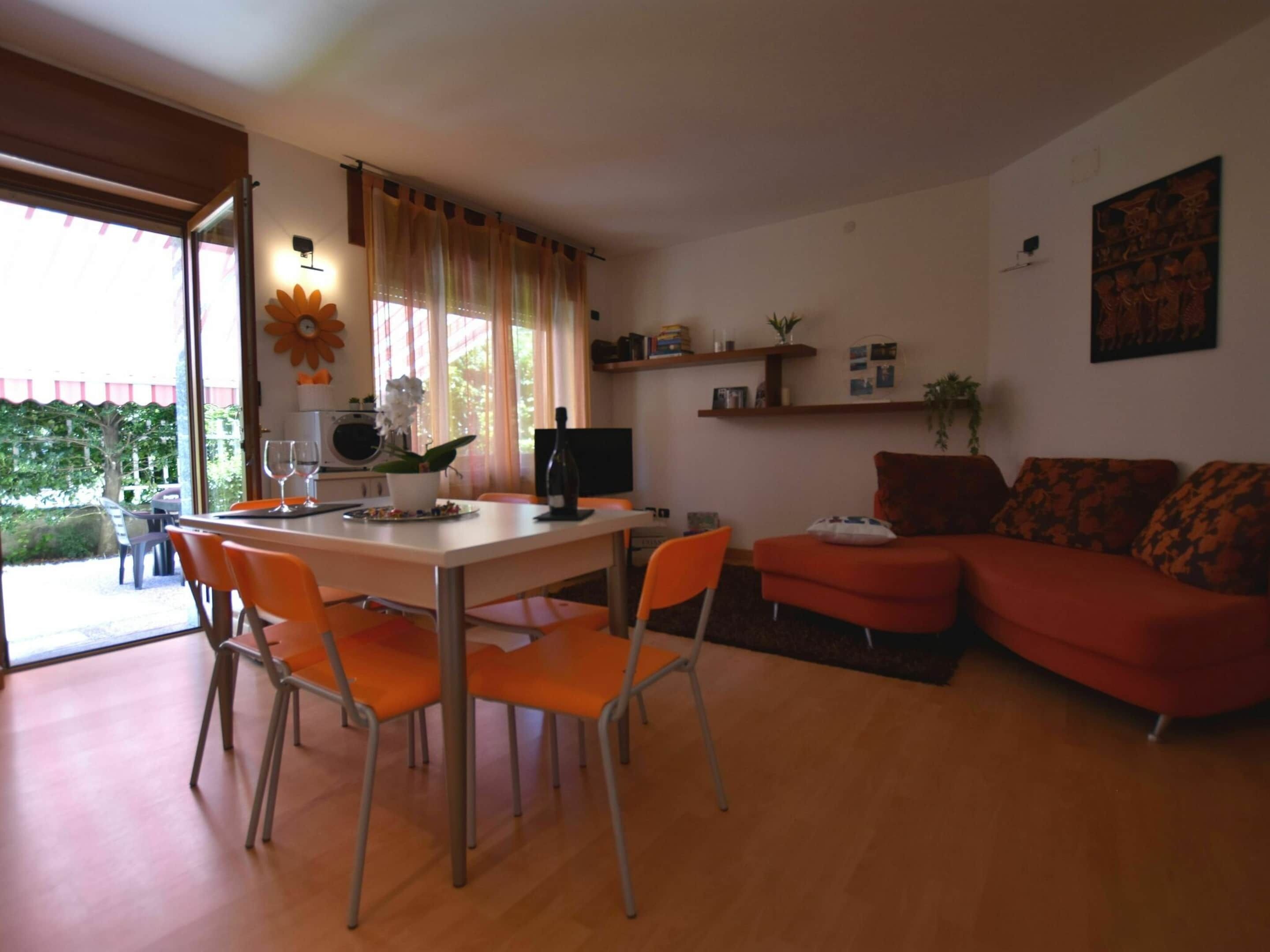 Een woonkamer met een eethoek, een bank, een televisie en een raam met gordijnen.