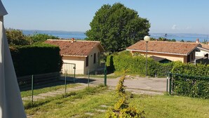 Una zona residencial con casas, un árbol grande y una vista despejada del mar.