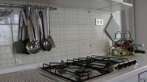 Una cocina con estufa a gas, utensilios colgantes y una bodega para vinos.