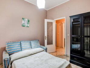 A bedroom with a bed, a wardrobe, a door leading to another room, and a wall with a framed picture. - City Apartment w/ Balcony (Syracuse)