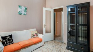 A room with a white sofa, a black cabinet, and a door leading to another room.