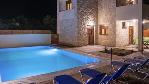 A modern building with a stone facade, a swimming pool, and outdoor seating. - Beach View Villa in Bali near City Center with Private Pool (Mylopotamos)
