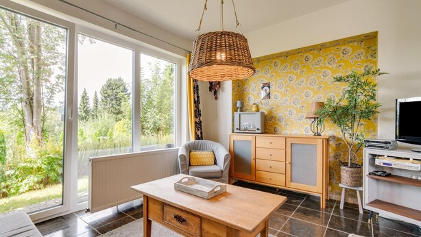 A modern living room with a large window, a wooden table, a sofa, a cabinet with a radio, and a television. - Inviting Holiday Home in Winterberg-Hildfeld near Ski Slopes (Winterberg)