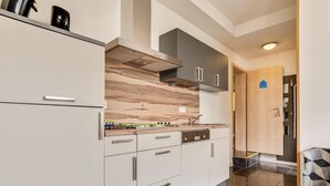A modern kitchen with white cabinets, a wooden backsplash, and a stainless steel range hood. - Inviting Holiday Home in Winterberg-Hildfeld near Ski Slopes (Winterberg)