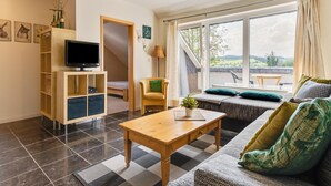 A modern living room with a TV, sofa, and a view of the outdoors. - Inviting Holiday Home in Winterberg-Hildfeld near Ski Slopes (Winterberg)