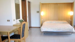 Ein Zimmer mit einem Bett, einem Schreibtisch, einem Stuhl und einem Spiegel.