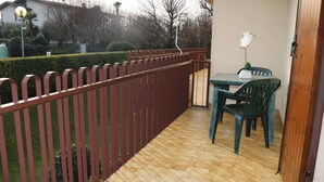 Ein Balkon mit Holzboden, rostem Metallgeländer und einem Tisch mit Stühlen.