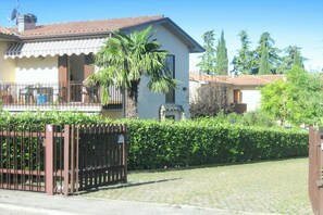 A residential building with a tiled roof, a balcony, and a palm tree in the yard.