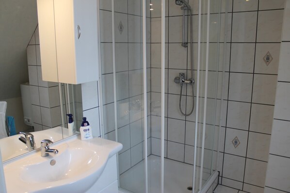 A bathroom with a white sink, a mirror, and a glass-enclosed shower area. - Attractive Apartment in Klütz near Sea (Klütz)