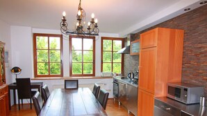 A modern kitchen with a wooden dining table, built-in cabinets, and a large window with a view of greenery. - Landhaus in Gressow mit Terrasse (Gaegelow)