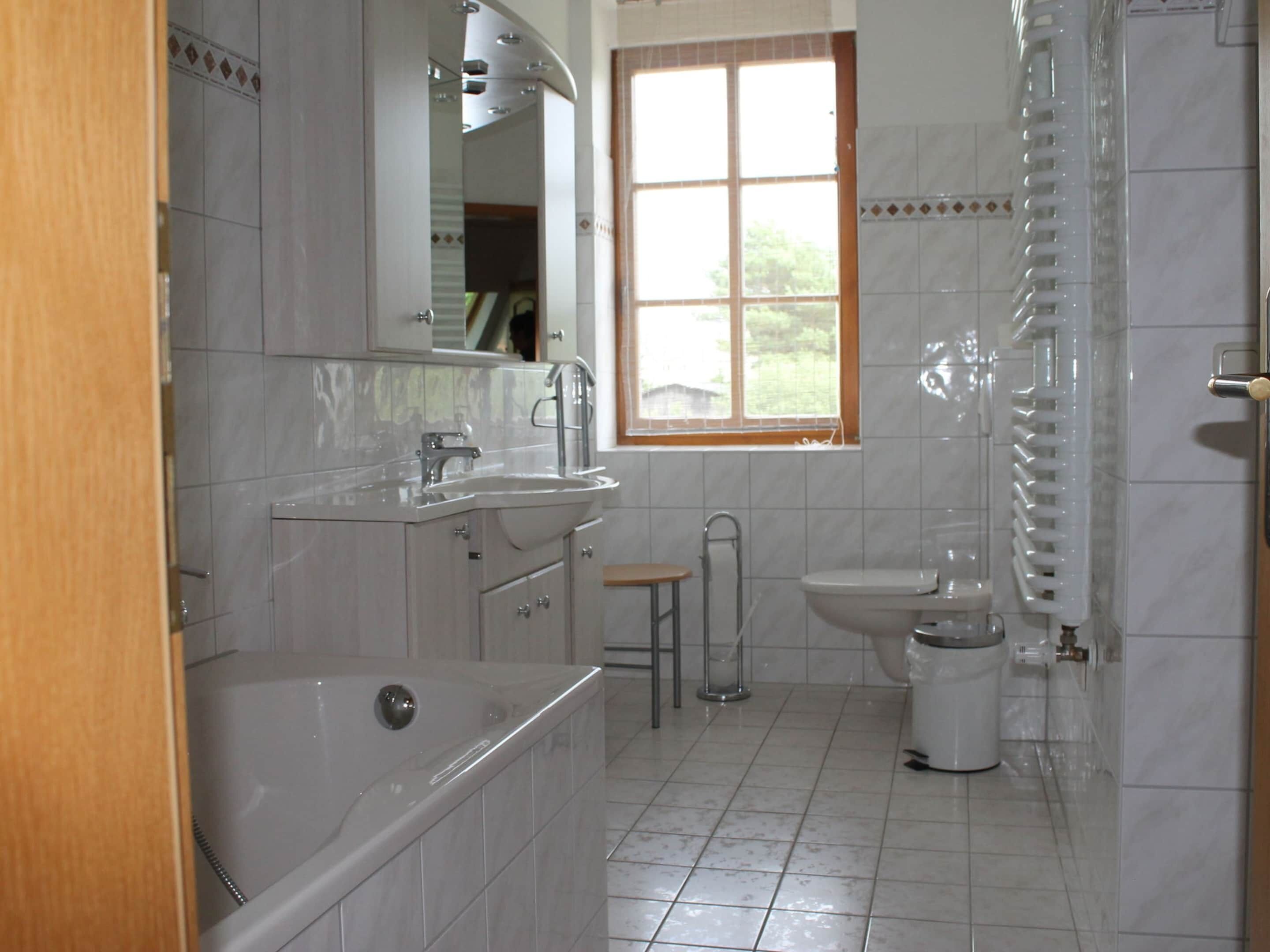 A bathroom with a bathtub, sink, toilet, and a window.