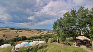 A pool area with umbrellas, a gazebo, and a view of rolling hills. - Flat in Piticchio With Scenic Views & Pool (Arcevia)