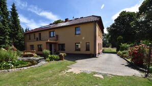 A two-story house with a paved driveway and a garden with flowers and a pond. - Einladende Ferienwohnung in Zweedorf mit Grill (Bastorf)