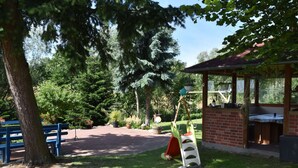 A park with a swing set, a covered seating area, and a brick building. - Einladende Ferienwohnung in Zweedorf mit Grill (Bastorf)