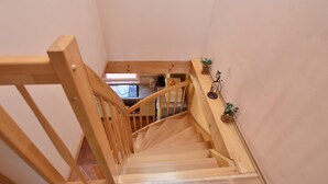 A wooden staircase with a handrail, leading to a kitchen area with a stove and cabinets. - Einladende Ferienwohnung in Zweedorf mit Grill (Bastorf)